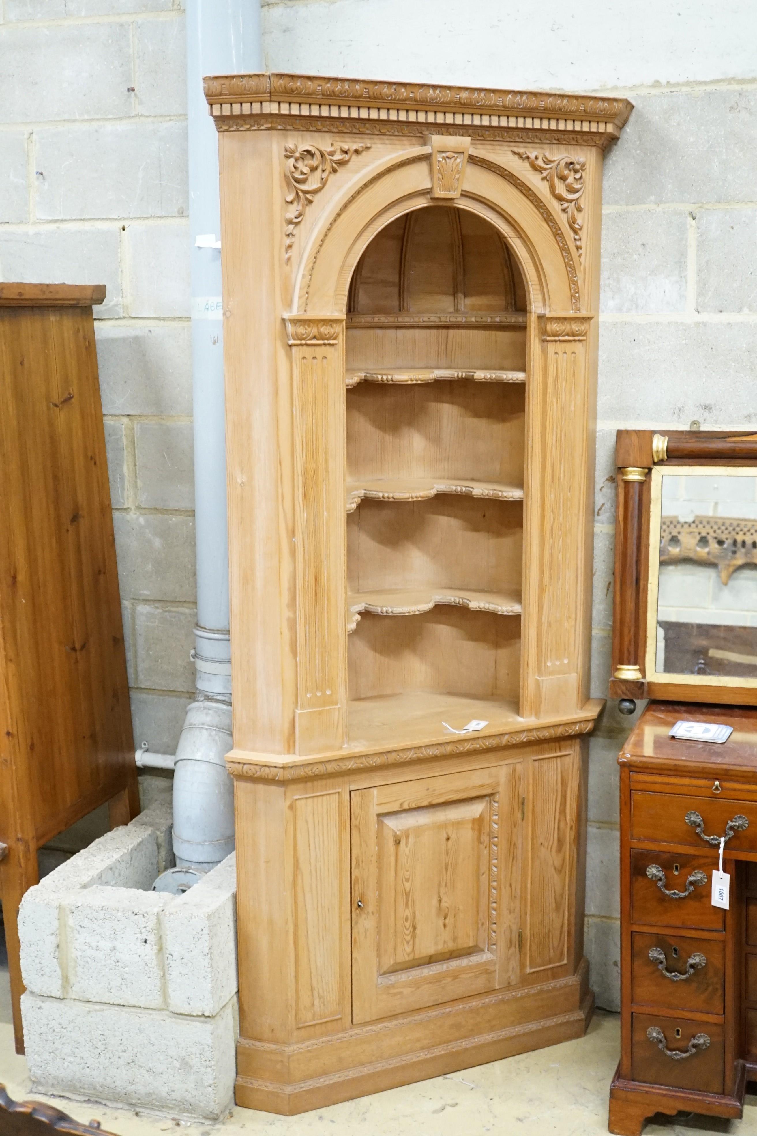 An 18th century style carved pine standing corner cupboard with arched shelved recess, width 94cm, height 204cm